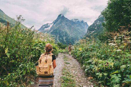 Family hikers with backpacks looking forward and walking to mountains, father with childの写真素材
