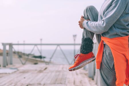 Fitness sport girl in fashion sportswear doing stretching exercise in the street. Outdoor workout in cold weather.の写真素材