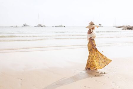 Girl wearing floral maxi skirt walking barefoot on the sea shore, Thailand, Phuket. Bohemian clothing style.の写真素材