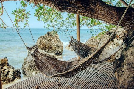 Two straw hammocks in patio on tropical beach, hot sunny dayの写真素材