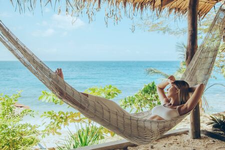 Woman relaxing in the hammock on tropical beach, hot sunny dayの写真素材
