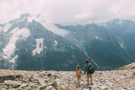 Father with child standing on the top of the mountain, winter hike with backpacks, alpine viewの写真素材