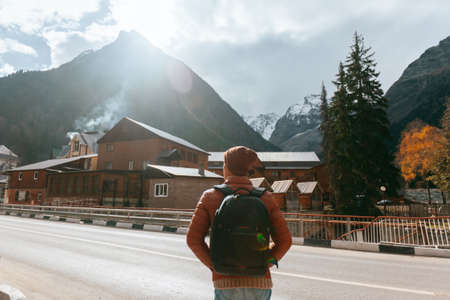 Teenage traveler standing and looking at village over mountains view. Student spending autumn or...
