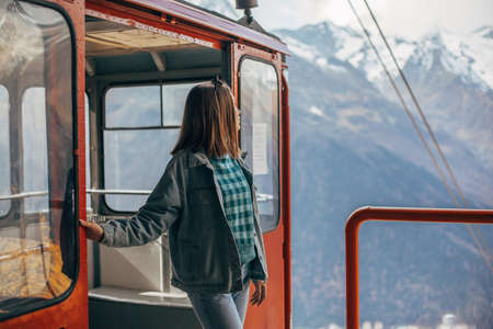 Young traveler looking at mountains view through sky lift window. Student girl spending her holidays in nordic country.の写真素材
