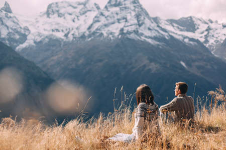 Two teenage friends dressed in warm fashion sweaters relaxing in mountains enjoying beautiful landscape and feeling freedom and happiness. Autumn trip to nordic countries.の写真素材