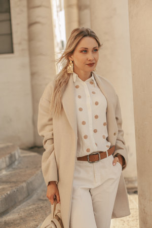 Fashion woman wearing beige trendy coat walking on the streetの写真素材