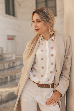 Fashion woman wearing beige trendy coat walking on the streetの写真素材
