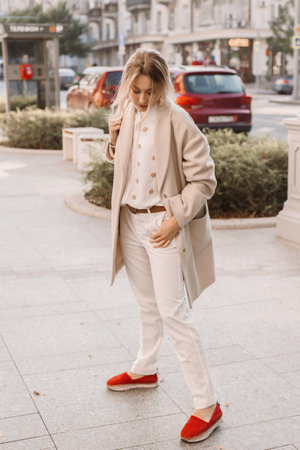Fashion woman wearing beige trendy coat walking on the streetの写真素材