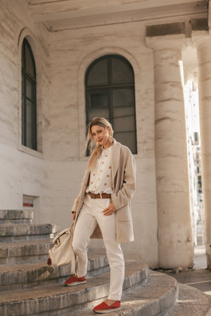 Fashion woman wearing beige trendy coat walking on the streetの写真素材