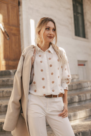 Fashion woman wearing beige trendy coat walking on the streetの写真素材