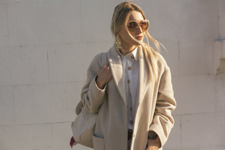 Fashion woman wearing beige trendy coat walking on the streetの写真素材
