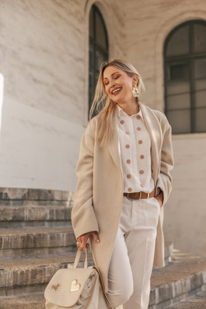 Fashion woman wearing beige trendy coat walking on the streetの写真素材