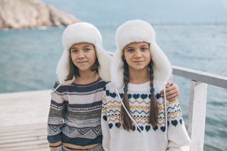 Children of one family wearing scandinavian clothing of same look travelling on the beach in the nordic cold country, they wear warm wool ornamental sweaters and fur winter hats.の写真素材