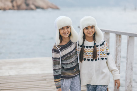 Children of one family wearing scandinavian clothing of same look travelling on the beach in the nordic cold country, they wear warm wool ornamental sweaters and fur winter hats.の写真素材