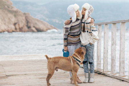 Family with dog wearing scandinavian clothing of same look travelling on the beach in the nordic cold country, they wear warm wool ornamental sweaters and fur winter hats.の写真素材