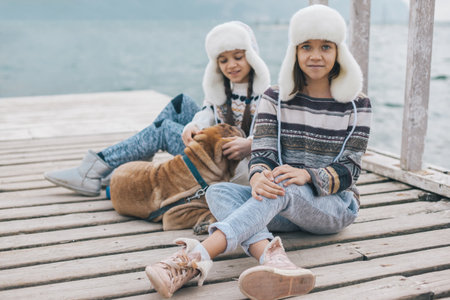 Family with dog wearing scandinavian clothing of same look travelling on the beach in the nordic cold country, they wear warm wool ornamental sweaters and fur winter hats.の写真素材