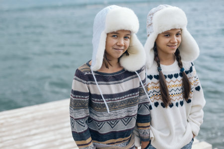 Children of one family wearing scandinavian clothing of same look travelling on the beach in the nordic cold country, they wear warm wool ornamental sweaters and fur winter hats.の写真素材