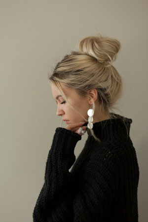 Beautiful young girl wearing warm black sweater and fashion jewellery over pastel background. Trendy minimal aesthetic style.の写真素材