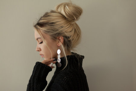 Beautiful young girl wearing warm black sweater and fashion jewellery over pastel background. Trendy minimal aesthetic style.の写真素材