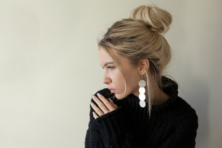 Beautiful young girl wearing warm black sweater and fashion jewellery over pastel background. Trendy minimal aesthetic style.の写真素材