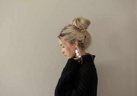 Beautiful young girl wearing warm black sweater and fashion jewellery over pastel background. Trendy minimal aesthetic style.の写真素材