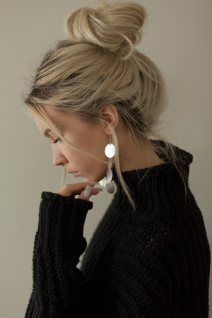 Beautiful young girl wearing warm black sweater and fashion jewellery over pastel background. Trendy minimal aesthetic style.の写真素材