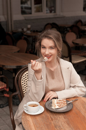 Young pretty elegant woman having a breakfast with tea and pie sitting on the terrace at the french cafeの写真素材