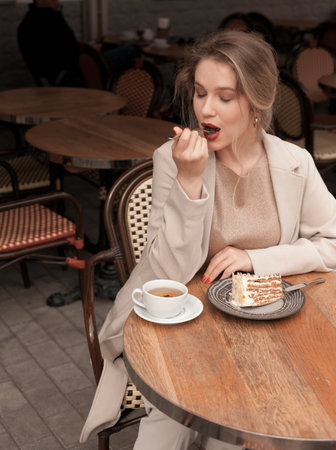Young pretty elegant woman having a breakfast with tea and pie sitting on the terrace at the french cafeの写真素材