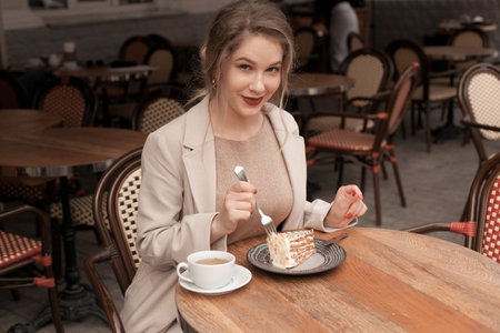 Young pretty elegant woman having a breakfast with tea and pie sitting on the terrace at the french cafeの写真素材