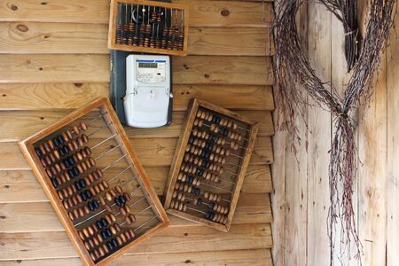 Old stone bills on a wooden wall, electric meter, birch branches, wreathの写真素材