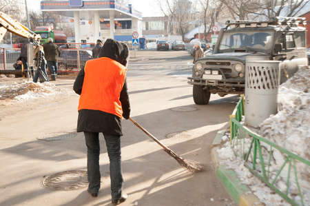 Moscow, Russia - March 03, 2010: Russian female street cleaner in orange suits are sweeping the ways and squares of the public place in Moscow.のeditorial素材