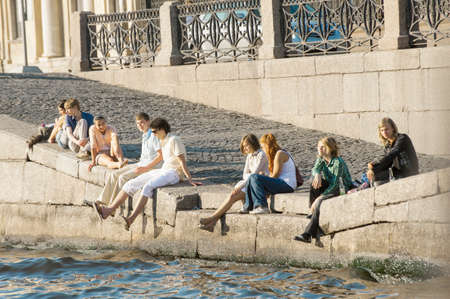 The group of young people has a rest in summer day on Neva River Embankment in Sankt Petersburg.のeditorial素材