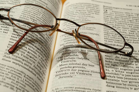 Round glasses lie on the bible in the Swedish languageの写真素材