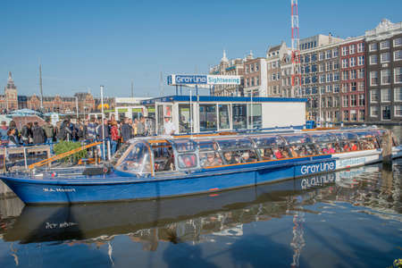Amsterdam, The Netherlands - April 05, 2014; Group of tourist take to board for a cruise canal in Amsterdam. Departure pier point is at the opposite Central Station.のeditorial素材