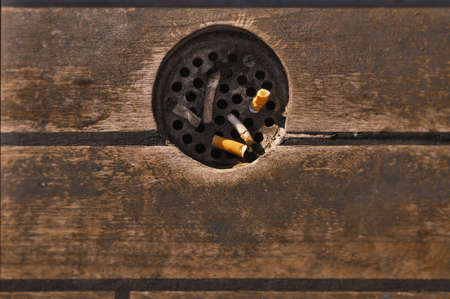 Street trash with ashtray and cigarette butts against the wooden floor.