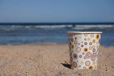 Concept Tourist Composition with coffee frappe ice coffee sun glasses and hat on the beach sand blue waters sea oceanの写真素材