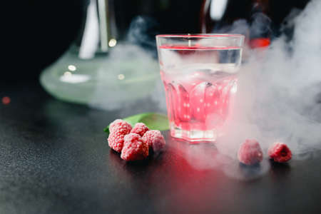 Famous color bright pink cocktails with alcohol, fruits and berries with rosemary and mint in dark...