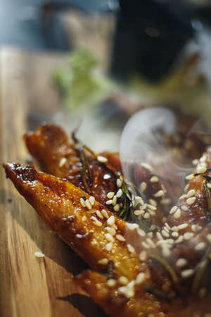 Fried chicken legs with teriyaki sauce sesame seeds and rice on black stoneの写真素材