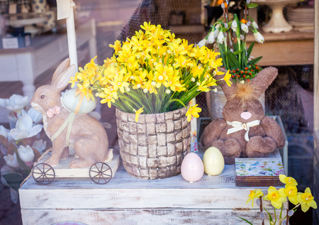 Easter theme in the showcase of a souvenir shop. Flowers, toys and Easter eggs on a chestの写真素材
