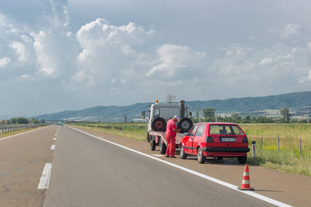 Vranje, Serbia â June 23, 2019: Towing service worker is going to load old damaged car on tow truck on highway. Old red Volkswagen Golfのeditorial素材