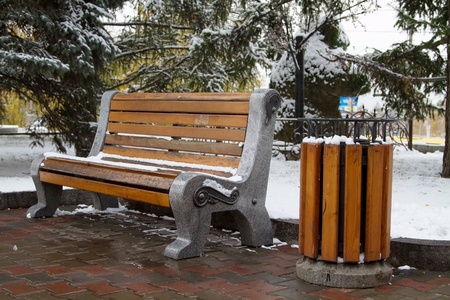 Wooden benches and garbage can covered with snowの写真素材