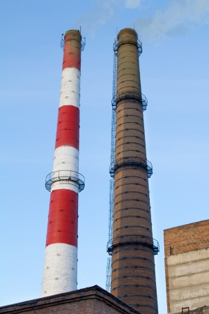 Two fuming factory chimneysの写真素材