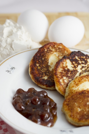 Curd pancake on a plate with strawberry jam and a handful of flour and egg の写真素材