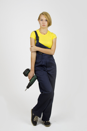 Young beautiful girl in blue overalls and yellow T-shirtの写真素材