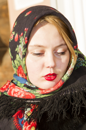 Pretty Slavic girl in a black coat and a colored scarfの写真素材