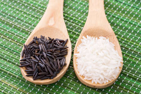 Two wooden spoons with black and white riceの写真素材