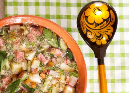 Okroshka on kvass in a ceramic bowl on a table and a wooden spoonの写真素材