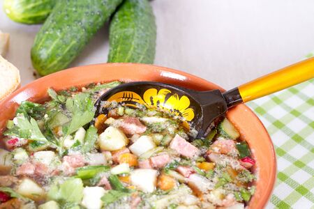 Okroshka on kvass in a ceramic bowl on a table and a wooden spoonの写真素材