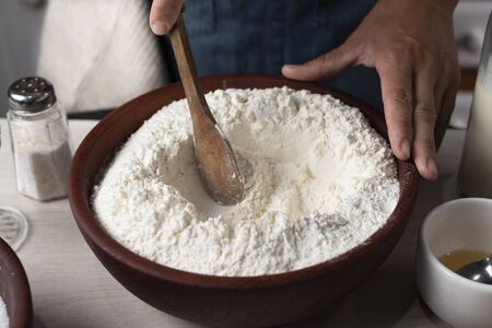 wooden spoon stirring flour