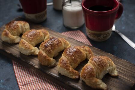 homemade croissants on wooden board with 2 cups for breakfast or snackの写真素材